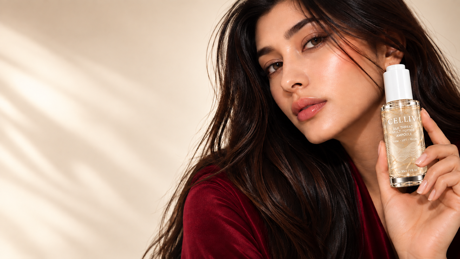 South Asian model in a deep cherry top holding the CELLIV Silk Thread Ampoule